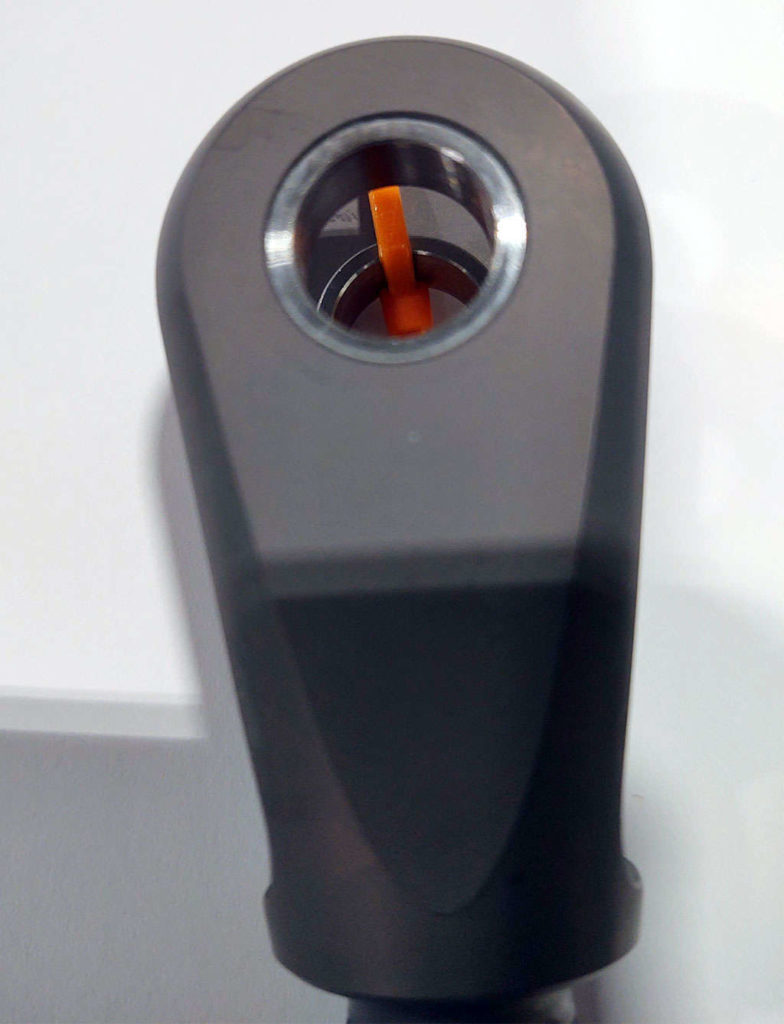 A close-up of a black car with an orange button, showcasing the bushing installation.