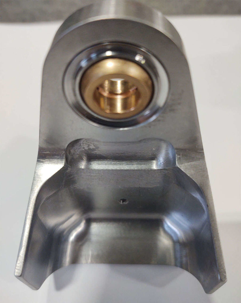 A gold ring encased stainless steel ball bearing holder along with a bushing for installation.